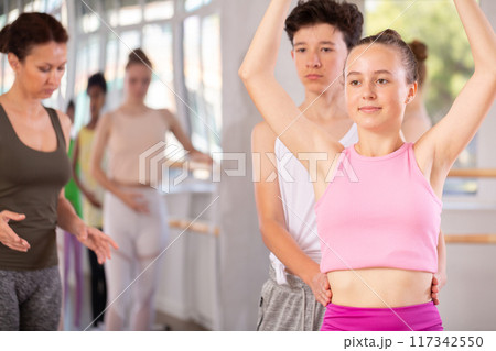 Teenage girl and boy practicing ballet moves in pair in dance studio Teenage girl and boy practicing ballet moves in pair in dance studio 117342550