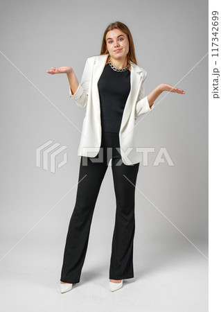 Young Woman Expressing Confusion With Hands Raised Against a Grey Background 117342699
