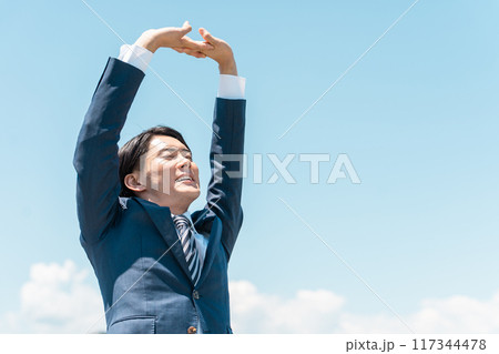 青空に向かって伸び・ストレッチをするビジネスマン（爽快・リフレッシュリ・リラックス・休み） 117344478
