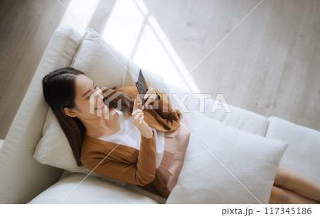 High angle view of happy cheerful positive young Asian woman on the phone at home 117345186