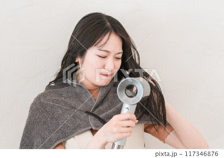 ヘアドライヤーでヘアブロー・髪の毛を乾かす女性（ヘアケア） 117346876