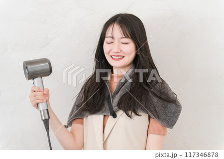 ヘアドライヤーでヘアブロー・髪の毛を乾かす女性（ヘアケア） 117346878