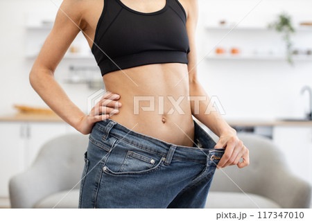 Person showing significant weight loss with oversized jeans 117347010