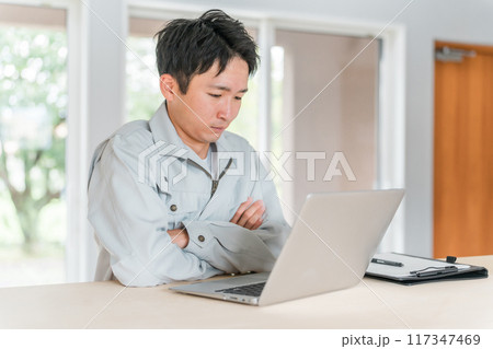 パソコン作業をする作業着・作業服姿の若いアジア人ビジネスマン 117347469