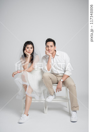 Happy young couple Asian groom and bride in casual wedding dress sitting on chair 117348806