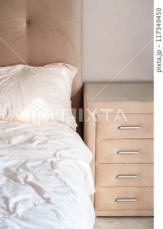 Cozy bedroom with beige headboard and dresser. Cozy bedroom with beige headboard and dresser. 117349450