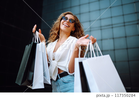 Young woman with shopping bags walking on street. Summer shopping. Sale, shopping, lifestyle concept Young woman with shopping bags walking on street. Summer shopping. Sale, shopping, lifestyle concept 117350284