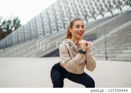 Young woman in sports outfit doing exercises outdoors in morning. Concept of sports, yoga or fitness Young woman in sports outfit doing exercises outdoors in morning. Concept of sports, yoga or fitness 117350449