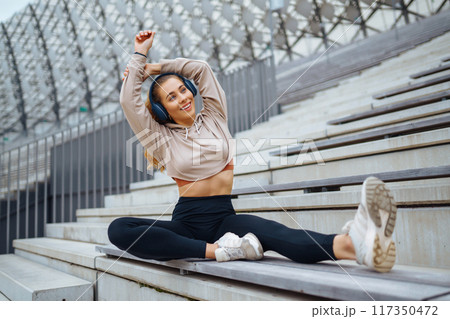 Young woman in sports outfit doing exercises outdoors in morning. Concept of sports, yoga or fitness 117350472