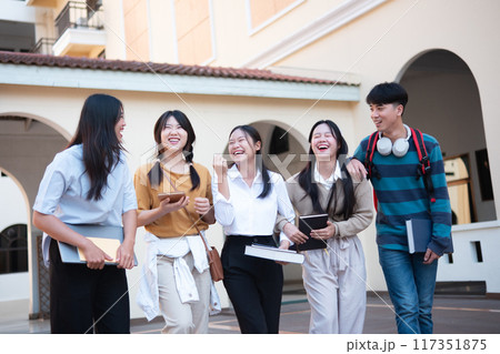 Campus students walking. College friends laughung while walking on campus. 117351875