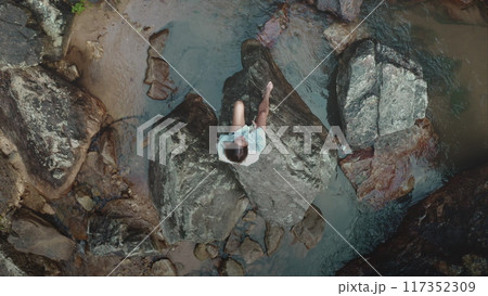 Relaxing woman on rocks in thailand's shallow waters, captured by drone, showing harmony of zen-like lifestyle. Explore peaceful moments in tropical paradise Relaxing woman on rocks in thailand's shallow waters, captured by drone, showing harmony of zen-like lifestyle. Explore peaceful moments in tropical paradise 117352309