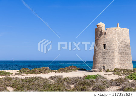 Ancient Torre de ses Portes on Ibiza coast with boats, sailboats dotting turquoise Mediterranean Sea Ancient Torre de ses Portes on Ibiza coast with boats, sailboats dotting turquoise Mediterranean Sea 117352627