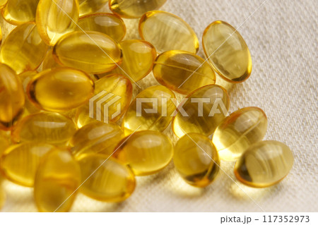 Golden soft gel capsules on a textile background. Nutritious diet vitamin pills 117352973