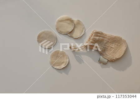 Bio organic cotton reusable round pads for make up removal and string bag in sunlight isolated on beige table background. Zero waste concept. Sustainable bathroom and lifestyle. Flat lay, top view. Bio organic cotton reusable round pads for make up removal and string bag in sunlight isolated on beige table background. Zero waste concept. Sustainable bathroom and lifestyle. Flat lay, top view. 117353044