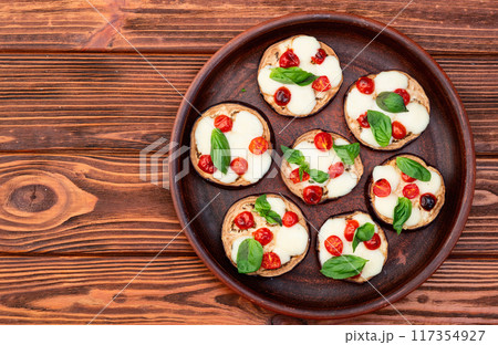 Italian mini pizza . Aubergine (eggplant ) with mozzarella cheese and basil . On rustic background Italian mini pizza . Aubergine (eggplant ) with mozzarella cheese and basil . On rustic background 117354927