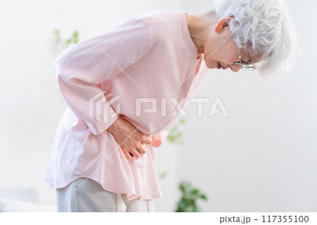 お腹を抱えるシニア女性	 117355100