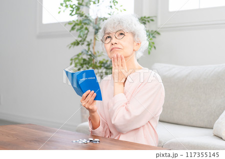 おくすり手帳を確認するシニア女性 おくすり手帳を確認するシニア女性 117355145