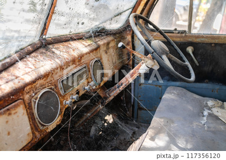 Abandoned old rusty car interior with dashboard and steering wheel 117356120