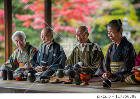 Visitors engage in the serene practice of a Japanese tea ceremony with vibrant autumn colors in the background Visitors engage in the serene practice of a Japanese tea ceremony with vibrant autumn colors in the background 117356398