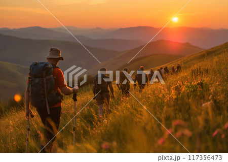 Group of hikers embarking on an early morning guided hike, surrounded by a golden sunrise over the hills 117356473