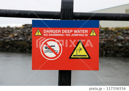 Danger Deep Water Signage at a Coastal Jetty on a Rainy Morning 117356556