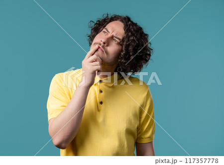 Curious thinking around curly man on blue. Confused student guy finding answer 117357778