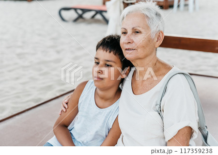 summer vacation at sea. Boy and senior woman at seaside. Grandmother with grandchild are resting on sea, running on beach having fun at summer holiday. Active parents, people activity with children. 117359238