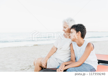 summer vacation at sea. Boy and senior woman at seaside. Grandmother with grandchild are resting on sea, running on beach having fun at summer holiday. Active parents, people activity with children. 117359240