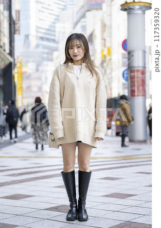 ニットのワンピースを着たカメラ目線で笑顔の20代の女性　 117359320