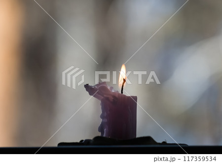 Burning candle on a table in a winter park. Shallow depth of field. 117359534