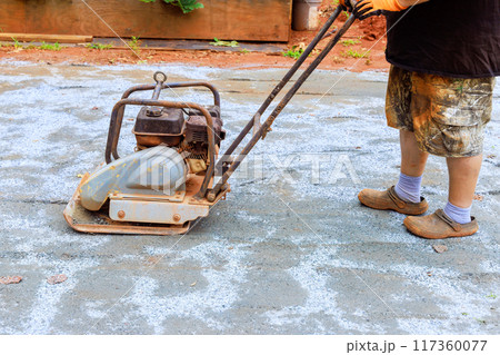 Vibratory tamping machine is used during construction for pool platform to compact sand 117360077