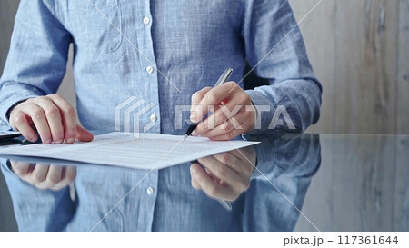 Businessman signing contract at desk. Close-up of a male executive signing a legal document on a glass desk. Business people concept Businessman signing contract at desk. Close-up of a male executive signing a legal document on a glass desk. Business people concept 117361644