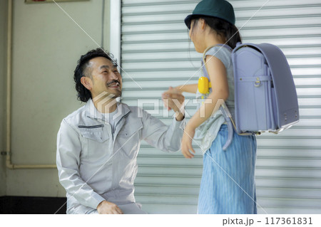 小学生の娘と話す作業着のパパ 117361831