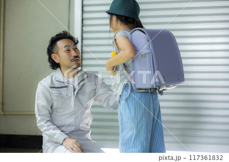 小学生の娘と話す作業着のパパ 117361832