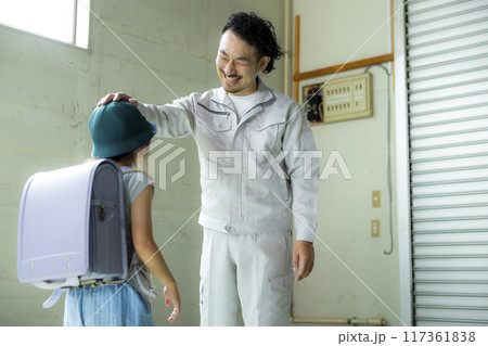 小学生の娘と話す作業着のパパ 117361838