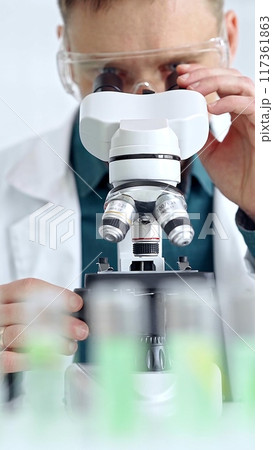 Man scientist with protective glasses using microscope in laboratory. Microbiology science concept 117361863