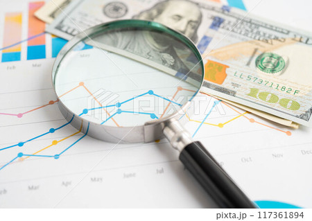 Magnifying glass with US dollar banknotes on graph. Finance business and trading. Magnifying glass with US dollar banknotes on graph. Finance business and trading. 117361894