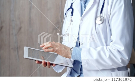 Doctor at work. Unrecognizable medical professional using digital tablet showcasing modern medical technology 117361970