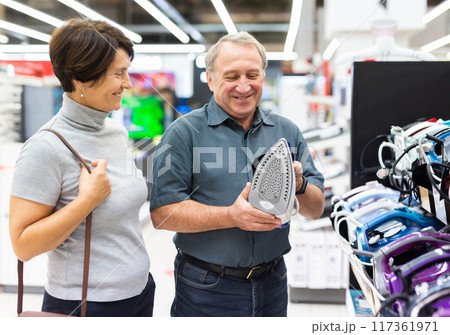 Elderly couple of customers looking for a deal on clothes irons in big electronics store Elderly couple of customers looking for a deal on clothes irons in big electronics store 117361971