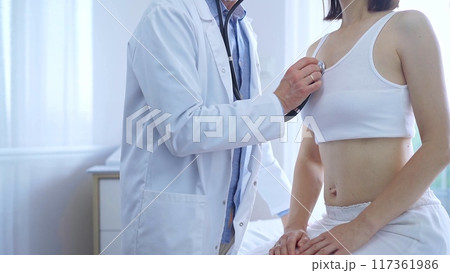 Doctor and patient. Physician is using stethoscope examining woman lungs in clinic cabinet. Medicine and health care Doctor and patient. Physician is using stethoscope examining woman lungs in clinic cabinet. Medicine and health care 117361986
