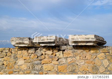 Fragments of ancient buildings, ruins of the ancient city of Hierapolis. Stone blocks with traces of stone machining. Fragments of ancient buildings, ruins of the ancient city of Hierapolis. Stone blocks with traces of stone machining. 117363285