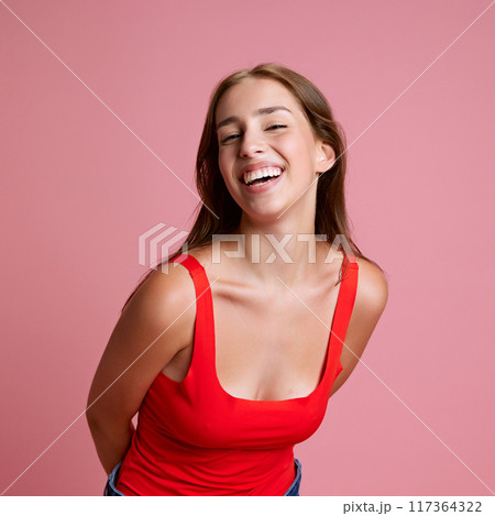 Portrait of beautiful young girl in red top cheerfully smiling, posing against pink studio background. Happiness, joy and fun Portrait of beautiful young girl in red top cheerfully smiling, posing against pink studio background. Happiness, joy and fun 117364322
