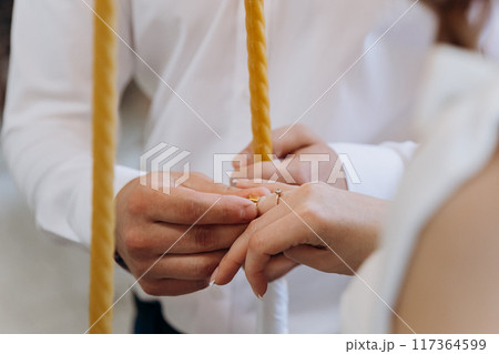 Beautiful close-up of a bride and groom exchanging wedding rings during a romantic ceremony 117364599