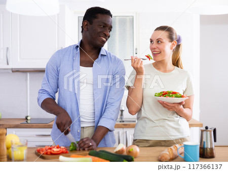 Positive couple cooking salad together at home Positive couple cooking salad together at home 117366137