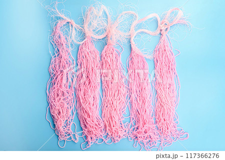 Top view of rows of pink beads on a blue background. 117366276