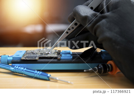 side view Technician is repairing Smartphone motherboard, circuit repair 117366921