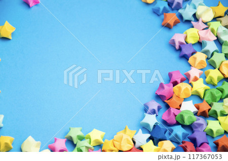 Paper folded into the shape of a multi-colored 5-pointed star, on a blue background. Paper folded into the shape of a multi-colored 5-pointed star, on a blue background. 117367053