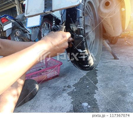 A motorcycle mechanic is patching a puncture in a tire. A motorcycle mechanic is patching a puncture in a tire. 117367074