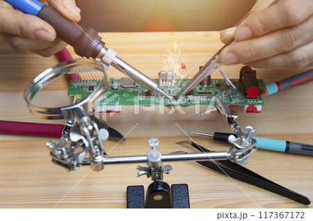 Technician is repairing motherboards and soldering equipment, repairing circuits. 117367172
