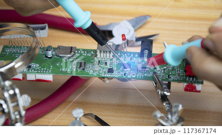 Technicians are repairing motherboards and checking electrical currents, repairing circuits. 117367174